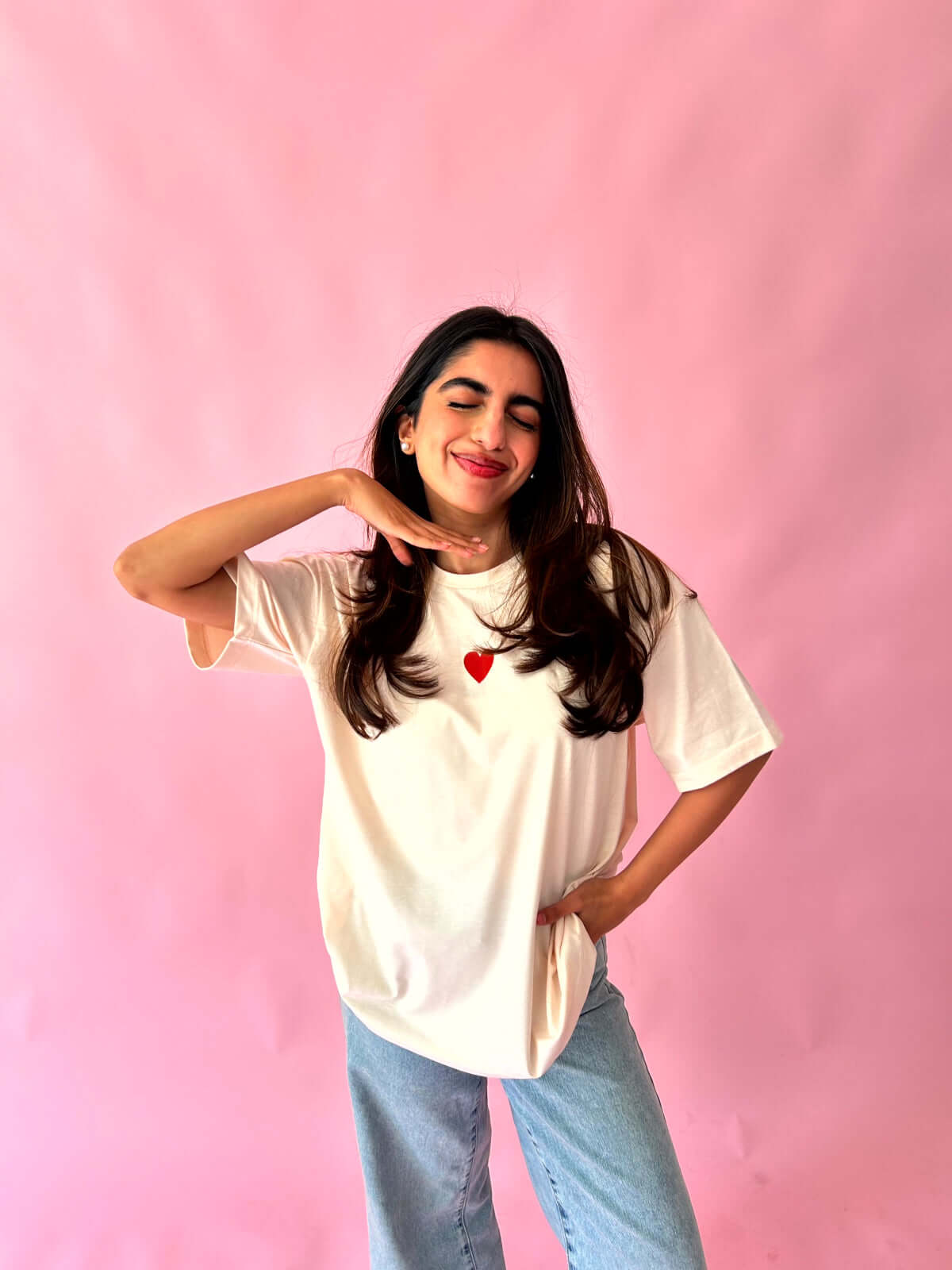 Woman wearing a soft pastel pink self love t-shirt with a heart design, showcasing confidence and style.