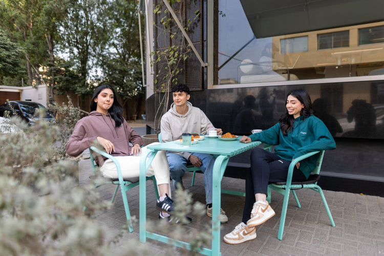 Unisex winter clothes: three models in Mocha Mousse, Cappuccino Beige and Jade Brew COZY hoodies at a café