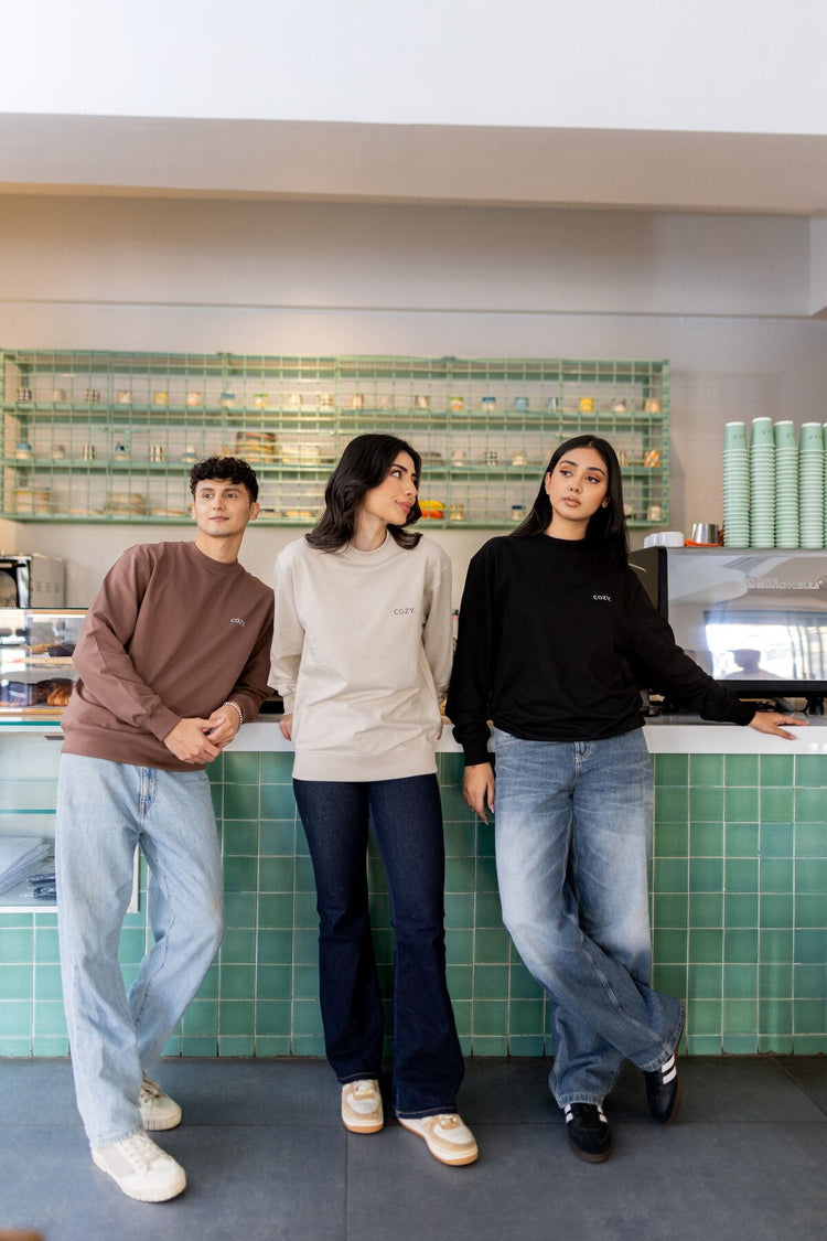 Unisex sweatshirts: three models in COZY crew neck sweatshirts at a café