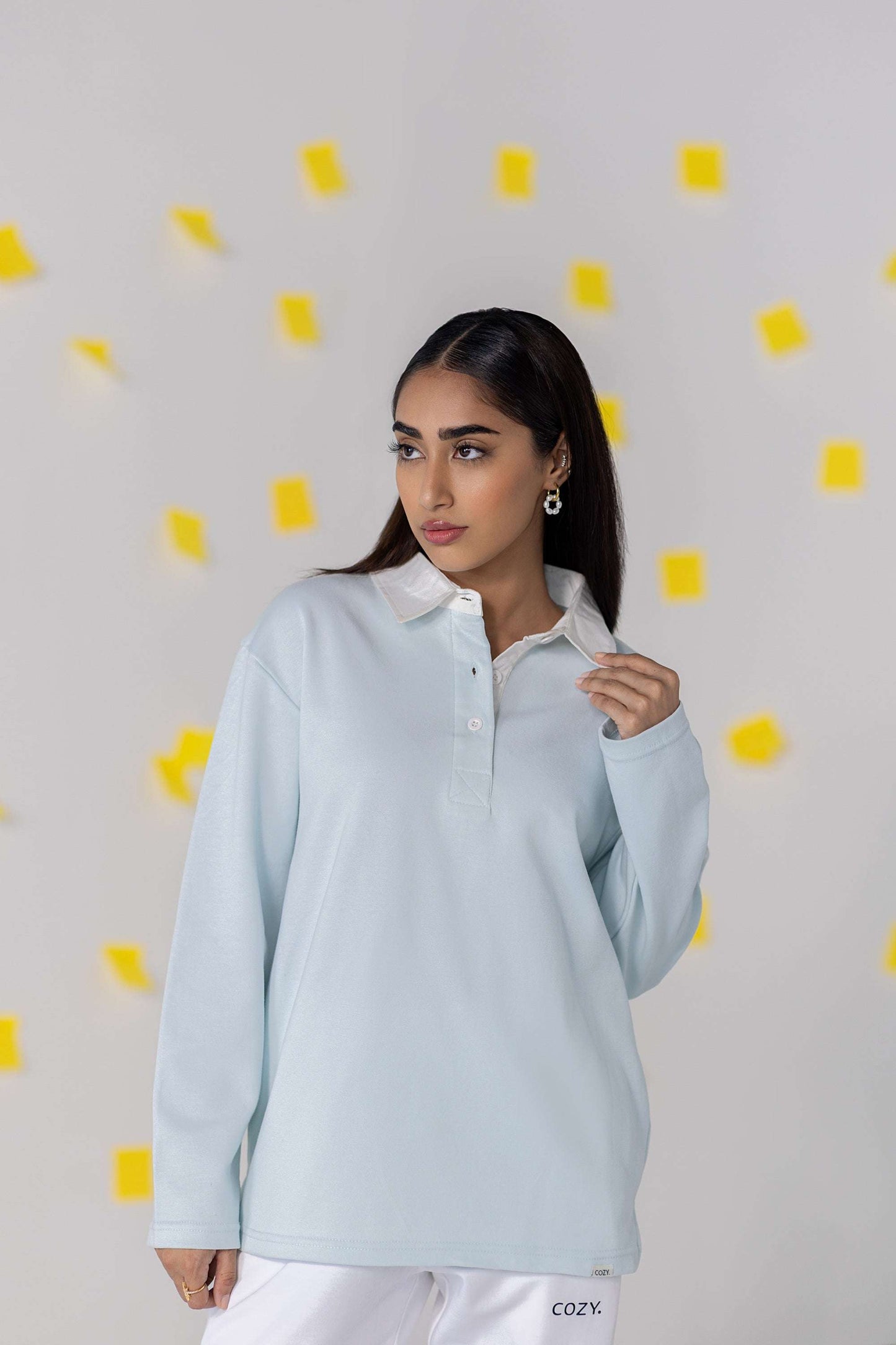 Woman wearing COZY Ladies Rugby Polo in light blue, showcasing relaxed fit and modern style with organic cotton blend.