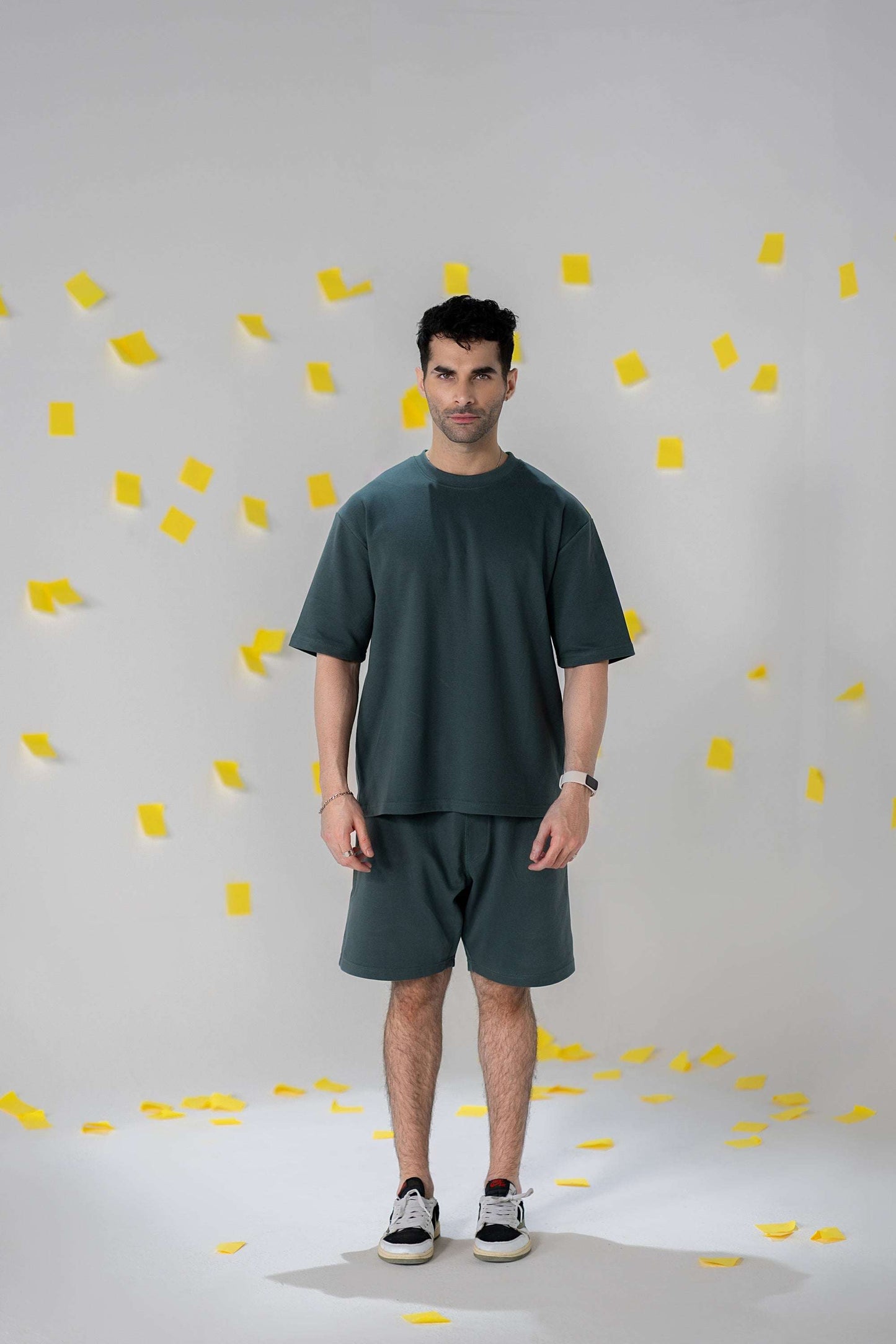 Model wearing COZY Shorts V2 and matching top in relaxed fit, surrounded by yellow paper confetti.