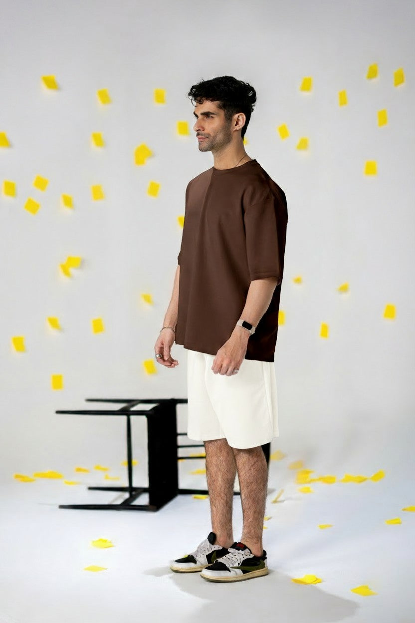 Man wearing COZY Shorts V2 with a relaxed fit and organic cotton blend, standing amidst yellow paper confetti.