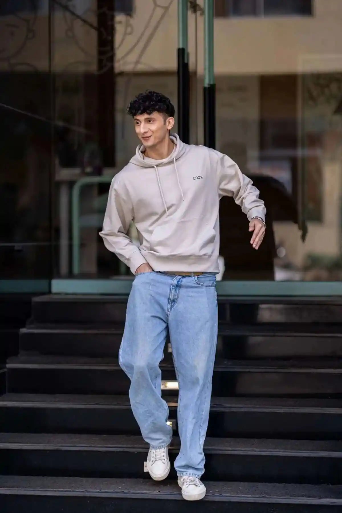 Man walking down dark steps in the COZY Men's Hoodie in Cappuccino Beige with light wash jeans and white sneakers