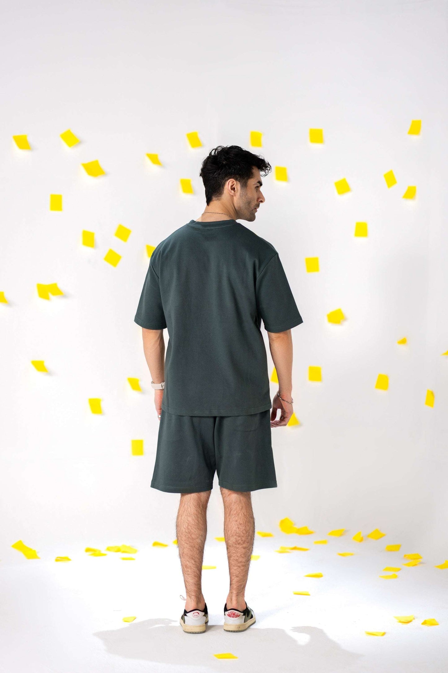 Man wearing COZY Shorts V2 and matching top, stylishly posed against a background of yellow paper confetti.