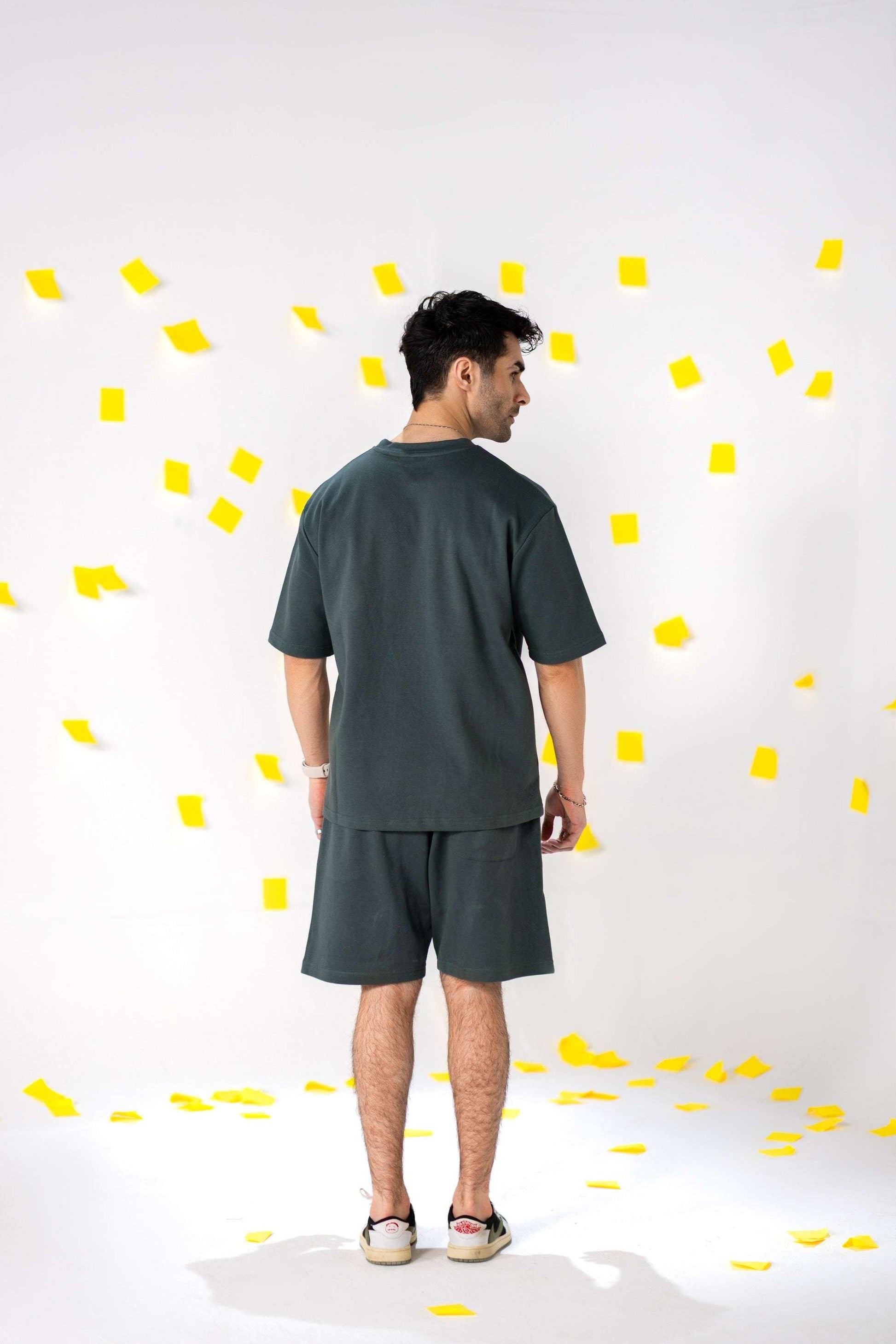 Man wearing COZY Shorts V2 and matching top, stylishly posed against a background of yellow paper confetti.