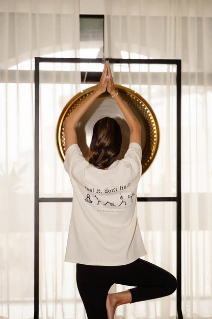 Feel It Don't Fix It oversized tee in cream COZY Cotton, back print model in tree pose